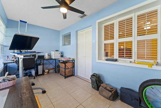 tiled home office with ceiling fan and a textured ceiling