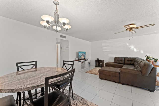 tiled dining room featuring ceiling fan with notable chandelier and a textured ceiling