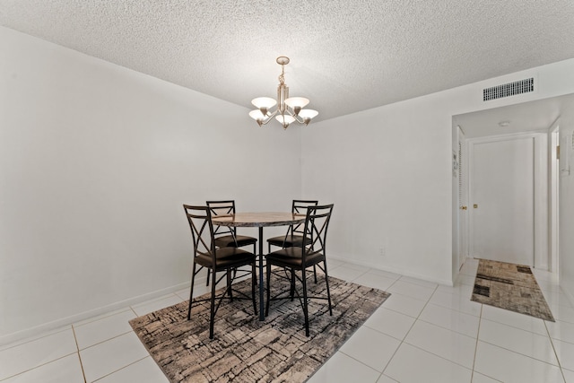 tiled dining area with a textured ceiling and an inviting chandelier