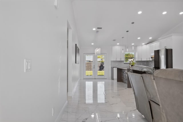 kitchen with tasteful backsplash, baseboards, marble finish floor, fridge, and white cabinetry