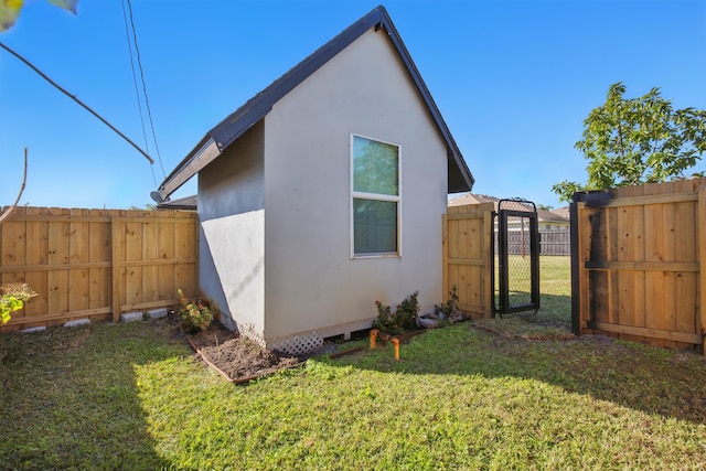 exterior space with a yard, an outdoor structure, fence, and stucco siding