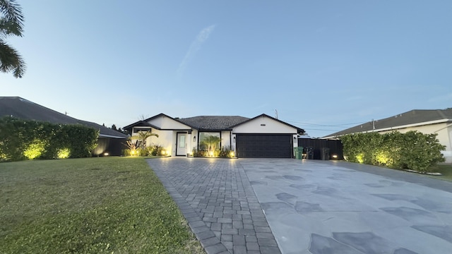 view of front of home featuring a garage, decorative driveway, and a front yard