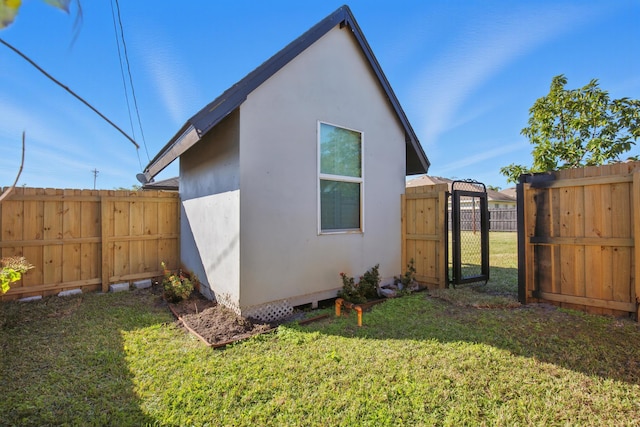 view of side of property featuring a gate, fence, a lawn, and stucco siding