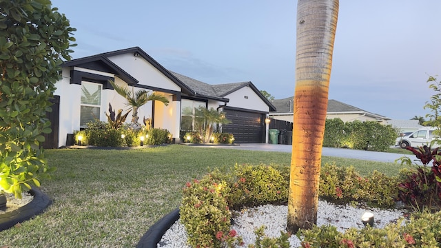 view of front facade featuring an attached garage, driveway, a front lawn, and stucco siding