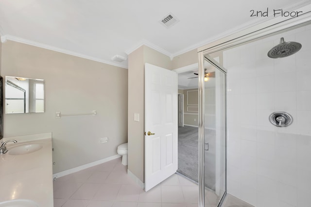 bathroom featuring vanity, tile patterned floors, crown molding, toilet, and a tile shower