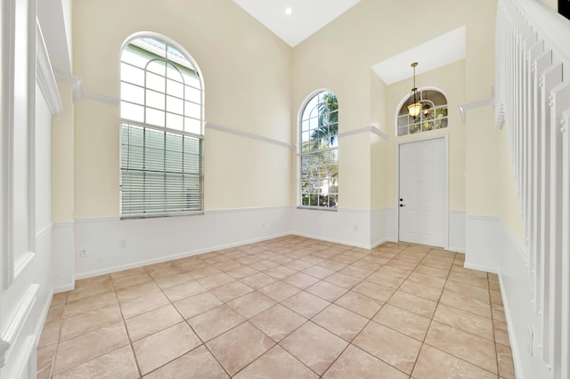 spare room with light tile patterned flooring, a high ceiling, and a chandelier