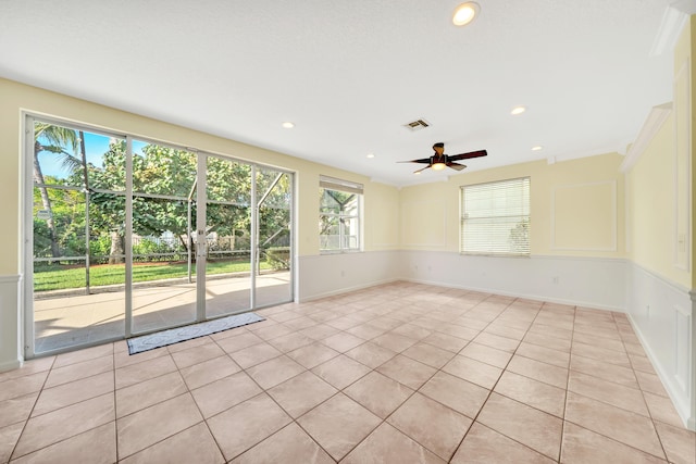 spare room featuring ceiling fan, light tile patterned floors, and a healthy amount of sunlight