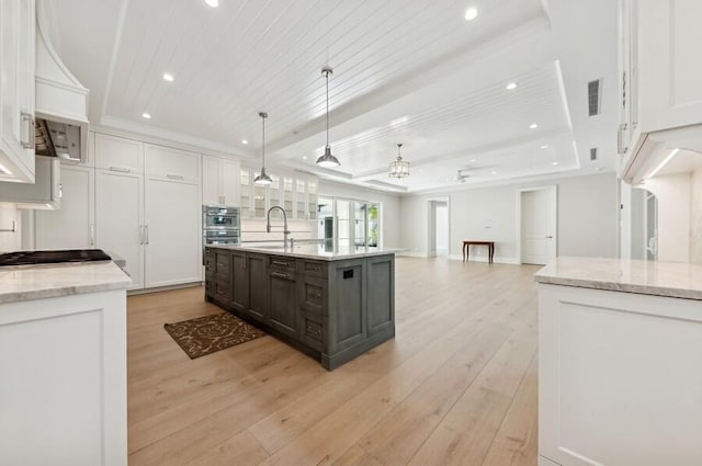 kitchen featuring wood ceiling, white cabinetry, an island with sink, and hanging light fixtures