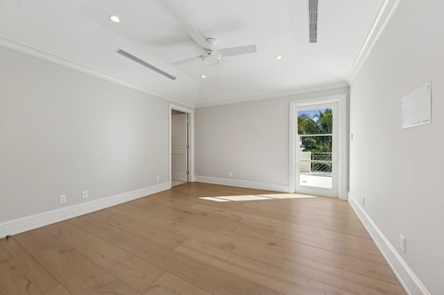 empty room featuring a tray ceiling, ceiling fan, light wood-type flooring, and ornamental molding