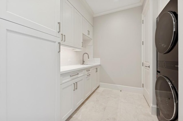 laundry room featuring sink, stacked washer and dryer, cabinets, and ornamental molding