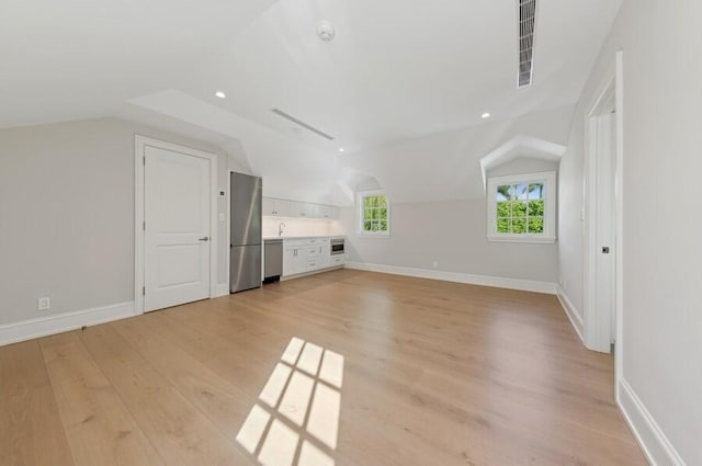 additional living space featuring light hardwood / wood-style floors, lofted ceiling, and sink