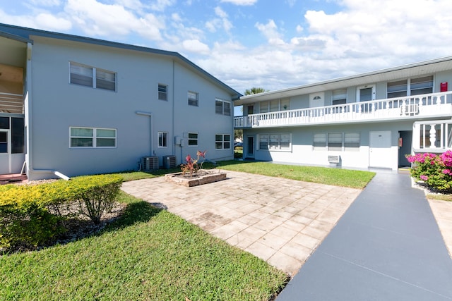 back of house with central air condition unit, a yard, and a patio