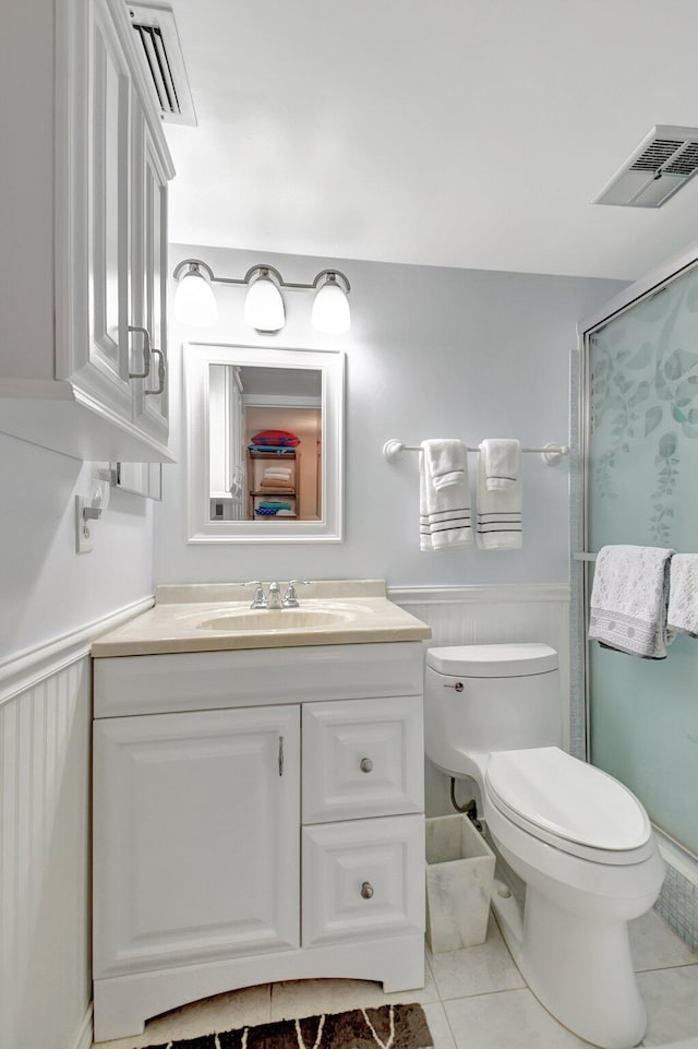 bathroom featuring tile patterned flooring, vanity, toilet, and an enclosed shower