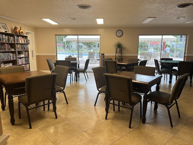 tiled dining room featuring a textured ceiling and crown molding