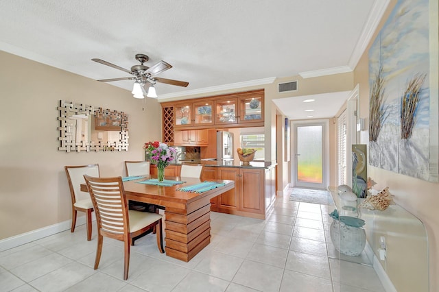 dining room featuring light tile patterned floors, a textured ceiling, ceiling fan, and crown molding