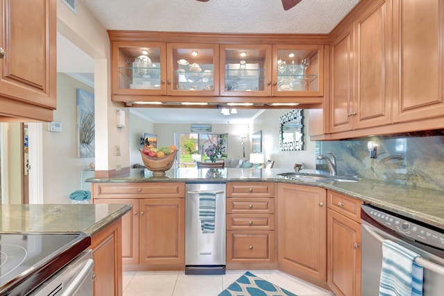 kitchen featuring stone counters, backsplash, stainless steel dishwasher, and sink