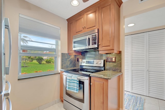 kitchen with stone countertops, stainless steel appliances, tasteful backsplash, and light tile patterned flooring