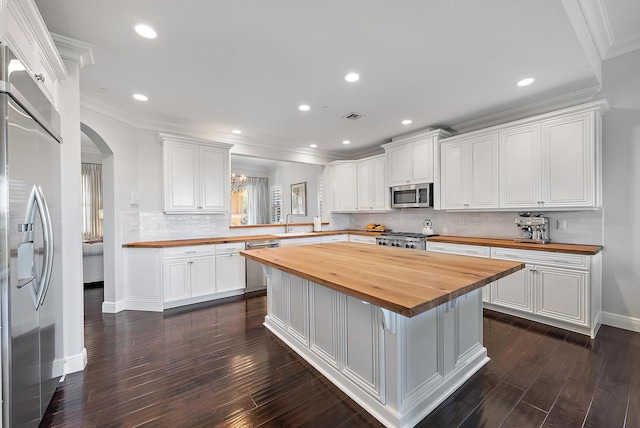 kitchen with a center island, wooden counters, white cabinets, kitchen peninsula, and stainless steel appliances