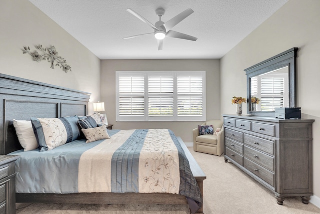 bedroom featuring multiple windows, a textured ceiling, light colored carpet, and ceiling fan