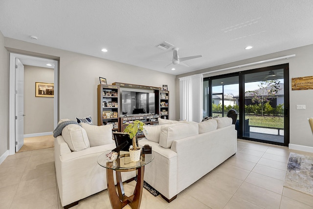 living room featuring ceiling fan, light tile patterned floors, and a textured ceiling