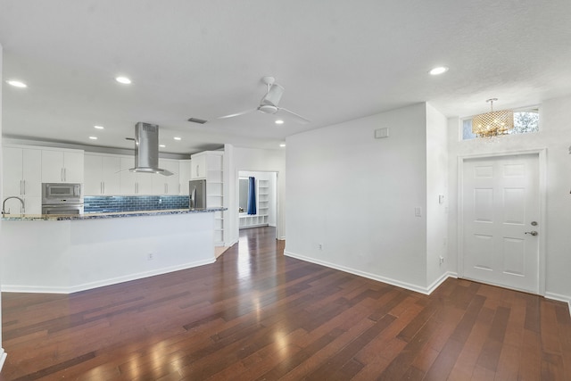 kitchen with white cabinetry, decorative light fixtures, stone countertops, island range hood, and appliances with stainless steel finishes