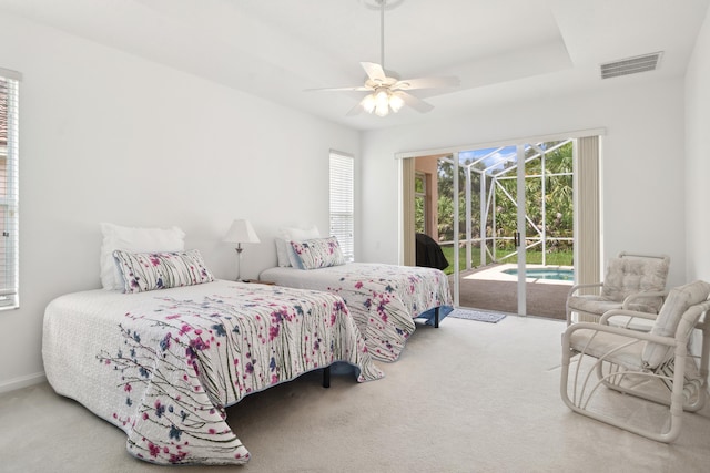 carpeted bedroom with a tray ceiling, access to exterior, and ceiling fan