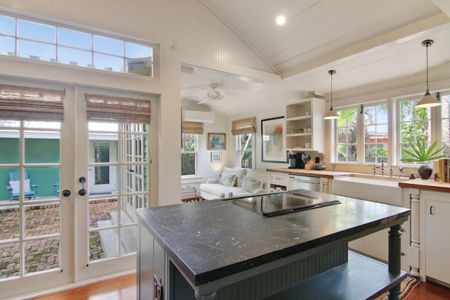 kitchen with a center island, light hardwood / wood-style flooring, a wall mounted AC, dark stone countertops, and decorative light fixtures