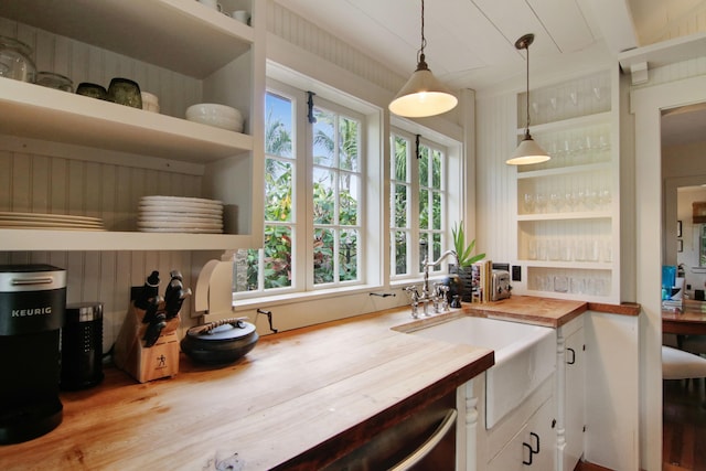 kitchen featuring butcher block counters, a healthy amount of sunlight, sink, and pendant lighting