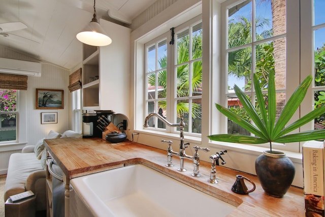 kitchen with wooden counters, sink, decorative light fixtures, an AC wall unit, and lofted ceiling