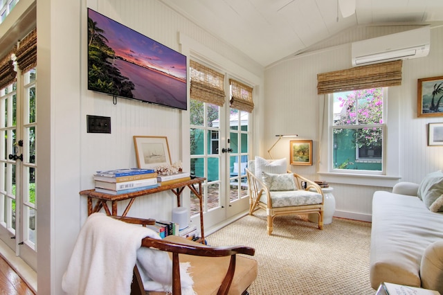 sitting room with lofted ceiling, a wall unit AC, and french doors