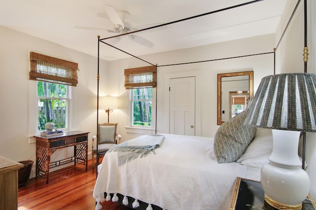 bedroom with ceiling fan, wood-type flooring, and multiple windows