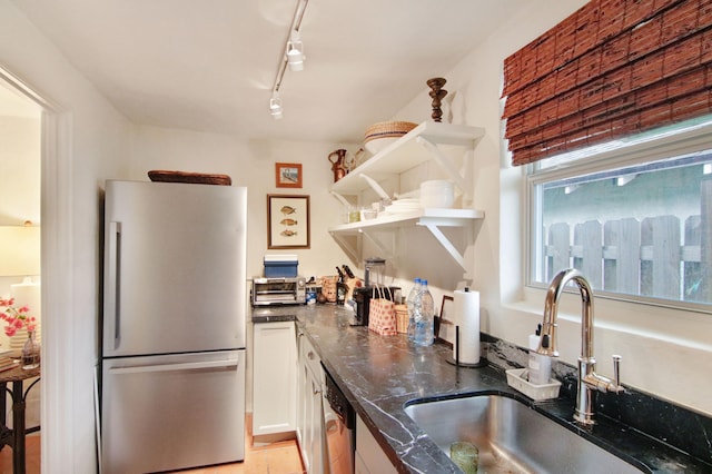 kitchen featuring sink, rail lighting, dark stone countertops, white cabinets, and appliances with stainless steel finishes