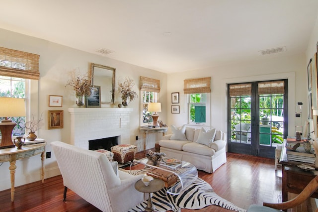 living room featuring french doors, dark hardwood / wood-style floors, and a brick fireplace