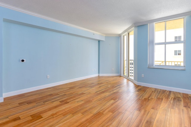 unfurnished room with light hardwood / wood-style floors, a textured ceiling, and ornamental molding