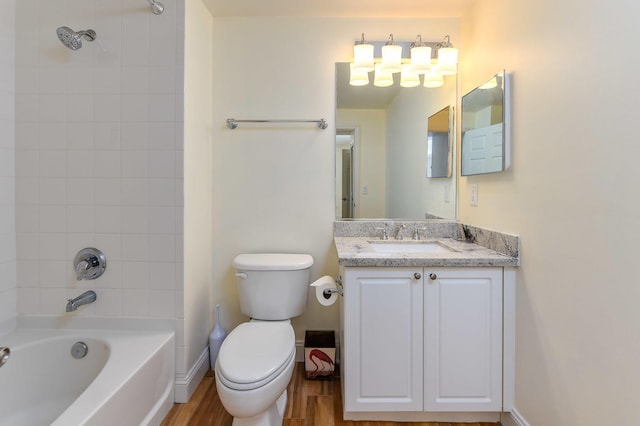 full bathroom with tiled shower / bath, hardwood / wood-style floors, vanity, and toilet