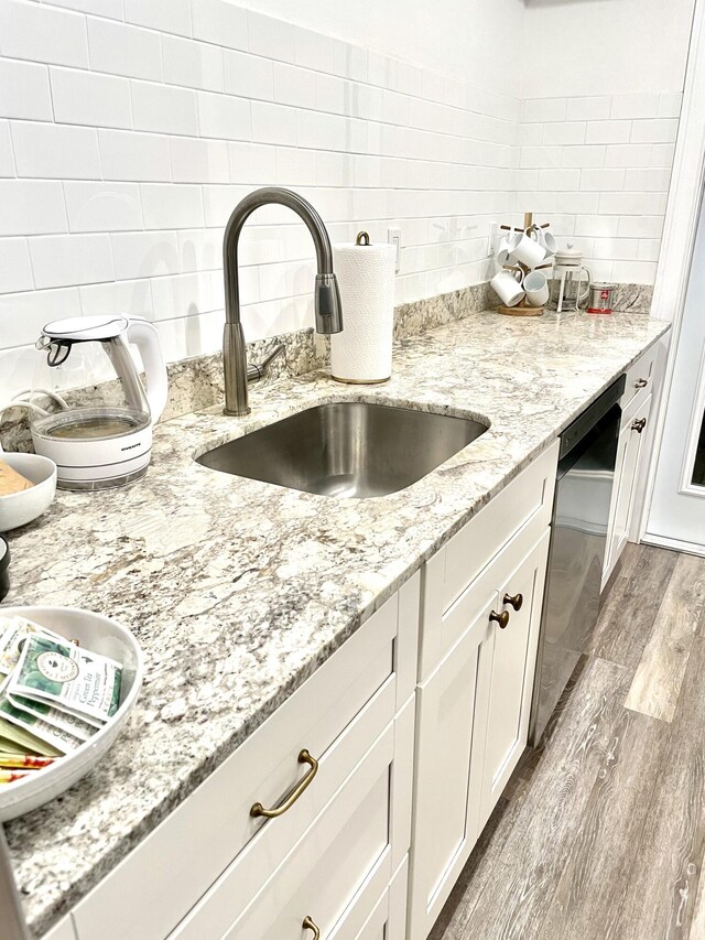 kitchen featuring white cabinets, dishwasher, light hardwood / wood-style floors, and light stone countertops