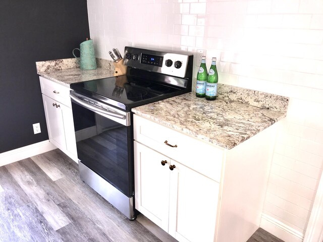 kitchen featuring white cabinetry, light stone counters, stainless steel electric range oven, and dark wood-type flooring