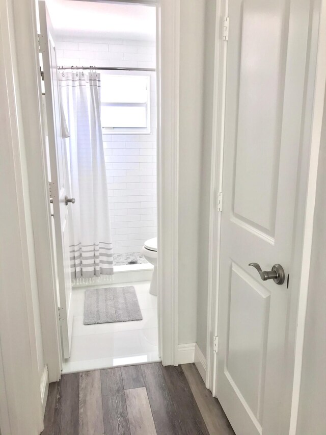 bathroom with toilet, hardwood / wood-style floors, and walk in shower