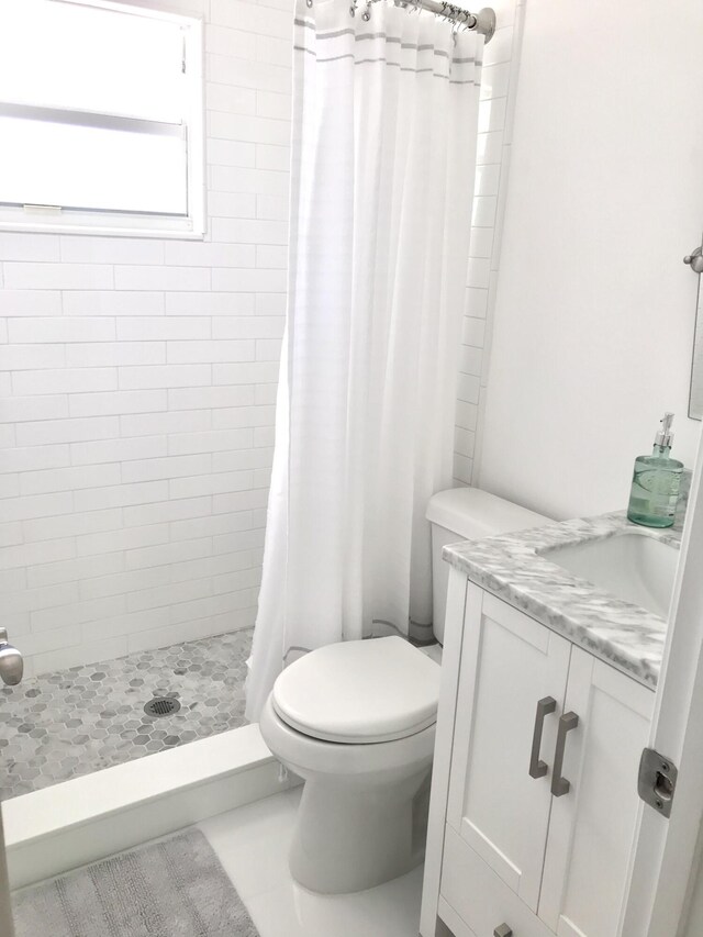 bathroom featuring tile patterned flooring, a shower with curtain, vanity, and toilet