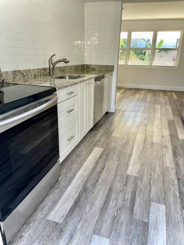 kitchen featuring sink, light wood-type flooring, light stone counters, white cabinetry, and stainless steel appliances