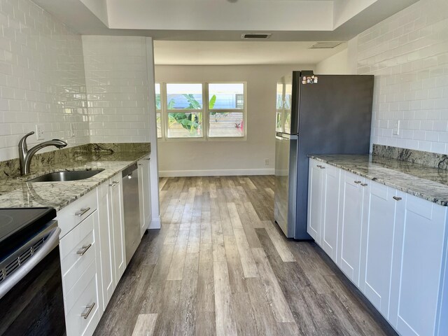 kitchen with white cabinetry, sink, light stone counters, and appliances with stainless steel finishes