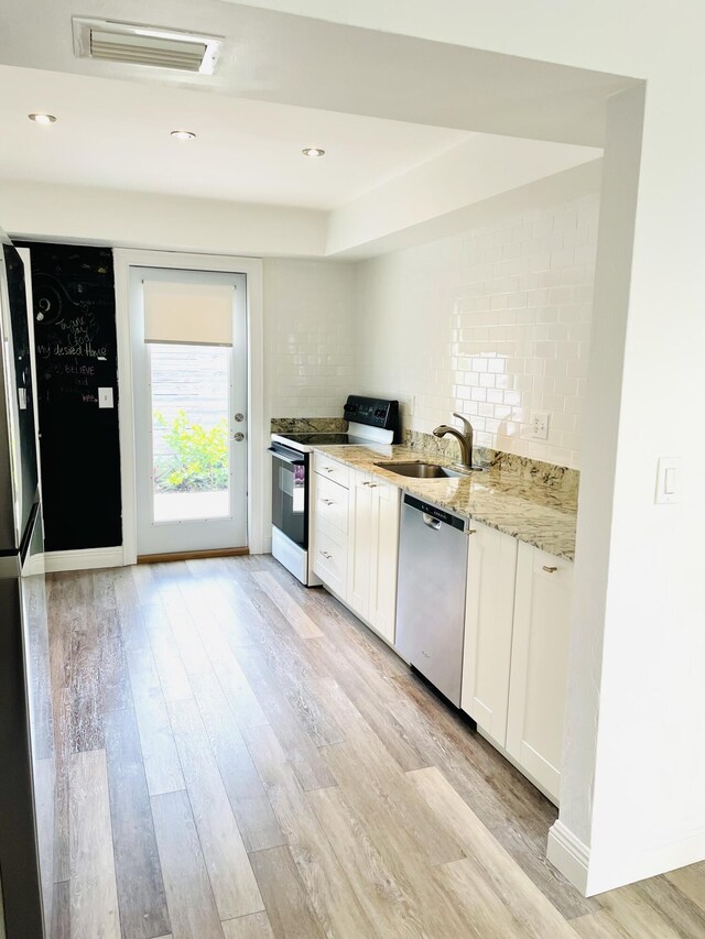 kitchen with sink, light stone counters, stainless steel dishwasher, electric stove, and white cabinets