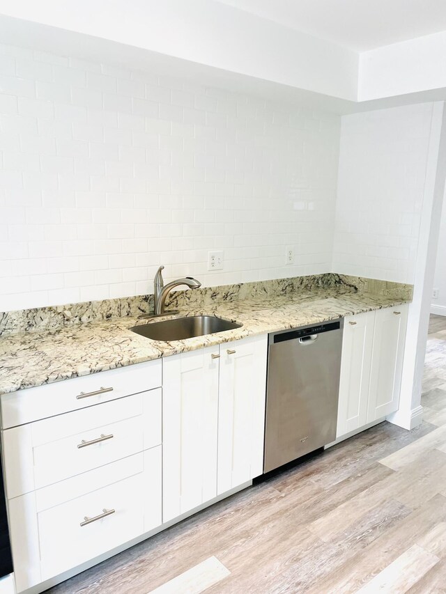 kitchen with dishwasher, white cabinets, sink, light stone countertops, and light hardwood / wood-style floors