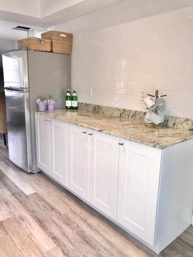 kitchen with white cabinetry, light hardwood / wood-style flooring, and light stone countertops