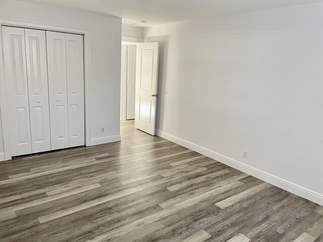 unfurnished bedroom with wood-type flooring and a closet