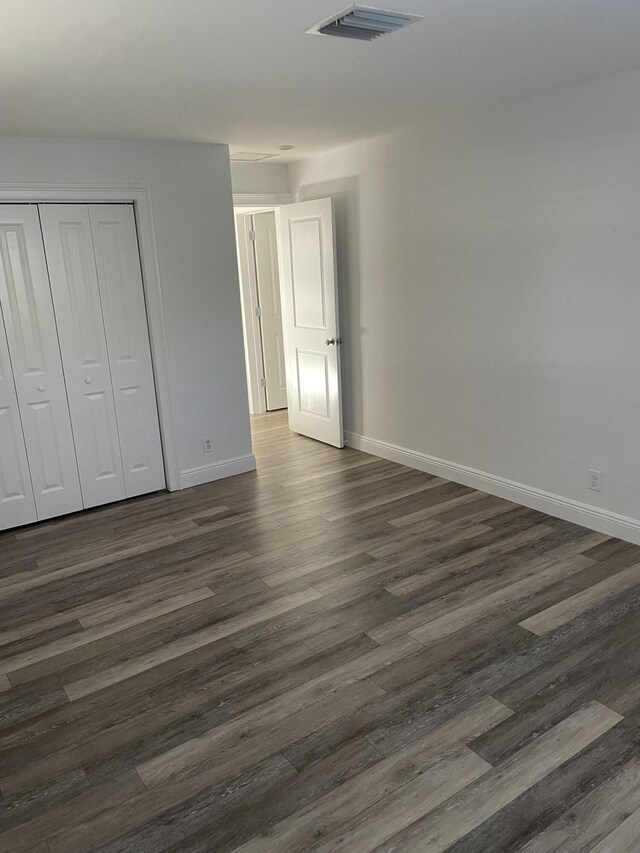 unfurnished bedroom with dark wood-type flooring and a closet