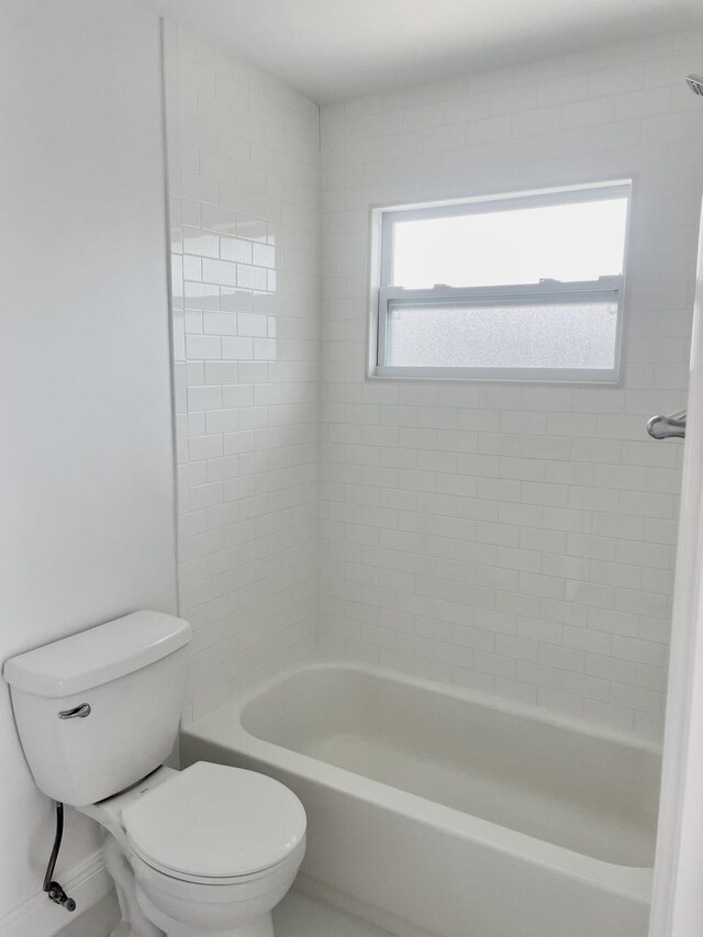 bathroom featuring toilet and tiled shower / bath