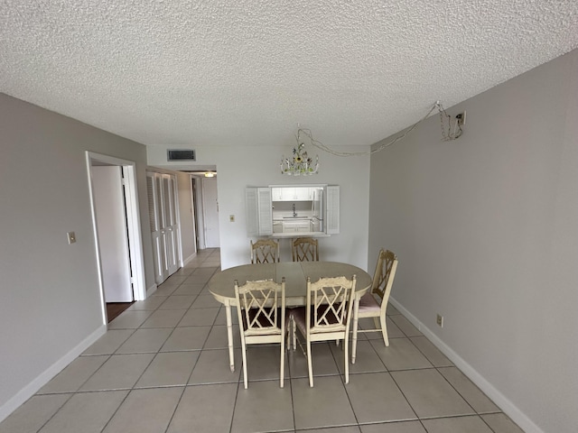 dining room featuring tile patterned floors, a notable chandelier, and a textured ceiling