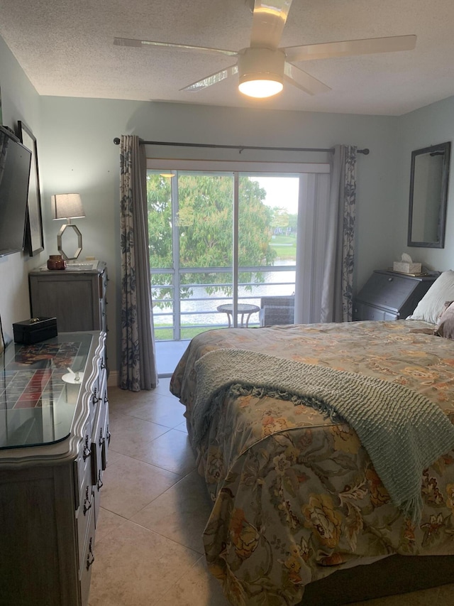 tiled bedroom with access to exterior, a textured ceiling, and ceiling fan