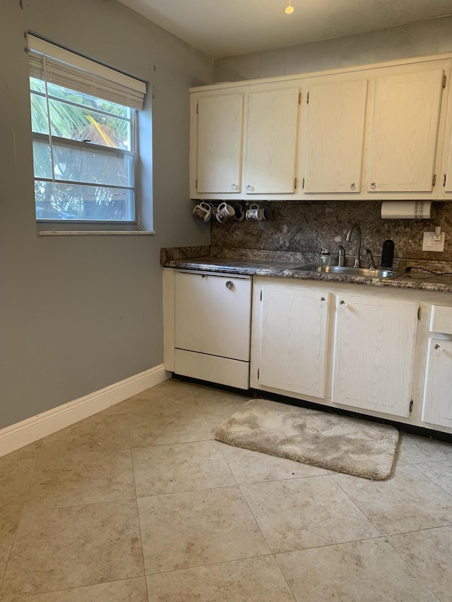 kitchen with dishwasher, sink, tasteful backsplash, dark stone counters, and light tile patterned floors